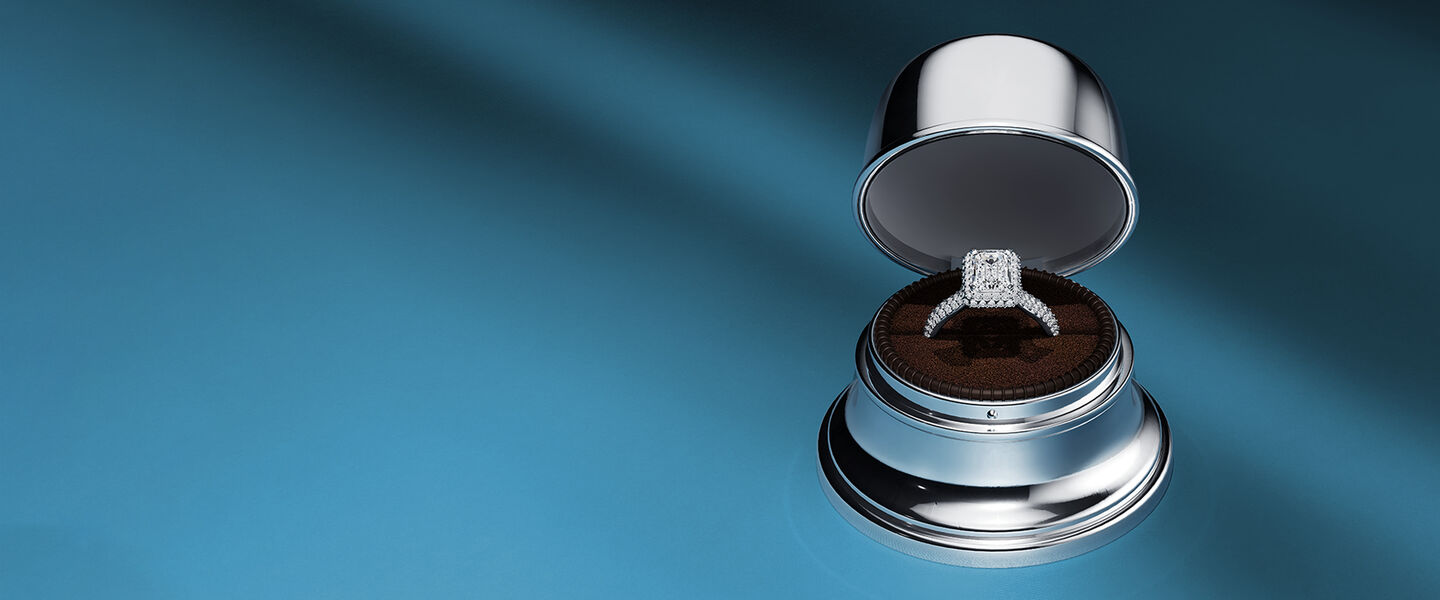 Une bague de fian&ccedil;ailles dans une bo&icirc;te &agrave; cloches Birks sur un fond bleu.